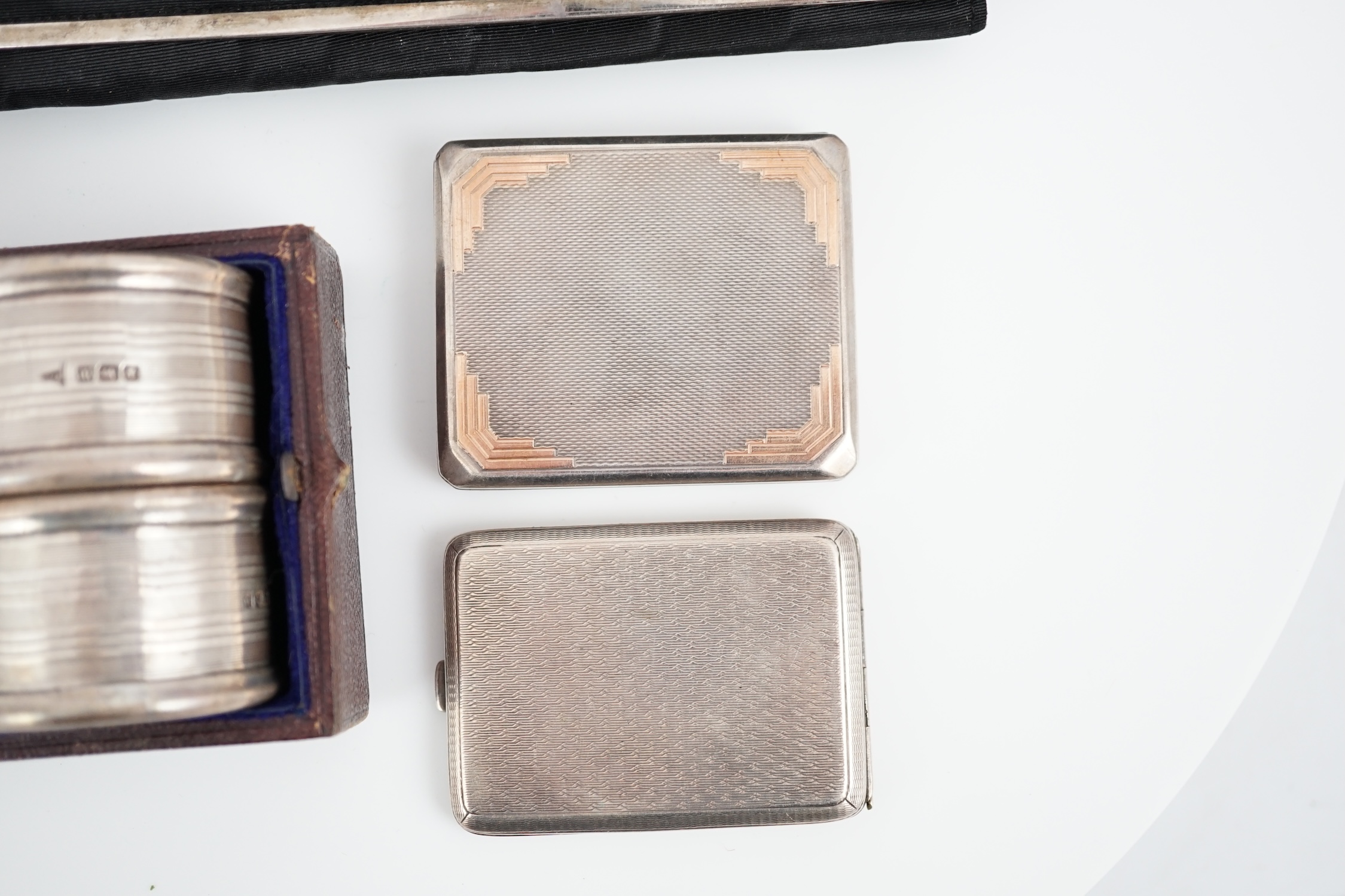 An Art Deco engine turned silver match sleeve by Asprey & Co, Birmingham, 1933, 6cm, together with one other silver match sleeve, a cased pair of silver napkin rings and a continental silver mounted four piece vanity set